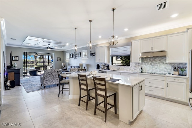 kitchen with pendant lighting, ceiling fan, a kitchen island, and white cabinets