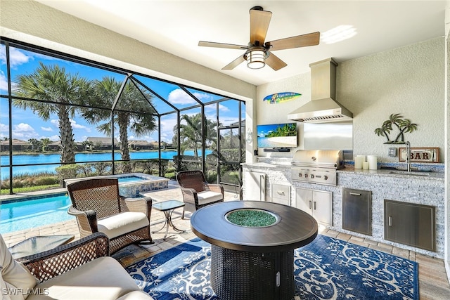 view of patio with grilling area, a water view, ceiling fan, a lanai, and exterior kitchen