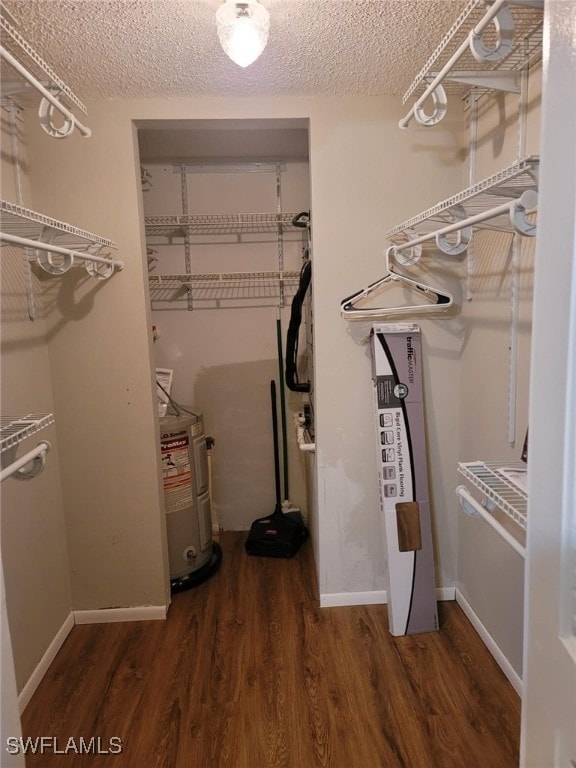 walk in closet featuring dark wood-type flooring and water heater