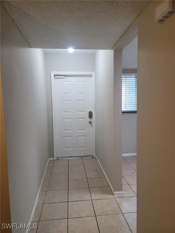 hall featuring a textured ceiling and light tile patterned floors