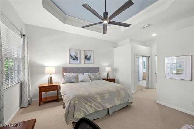 bedroom featuring a tray ceiling, ceiling fan, light carpet, and ornamental molding