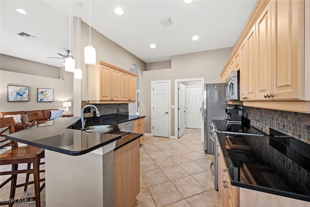 kitchen featuring pendant lighting, backsplash, a kitchen bar, kitchen peninsula, and stainless steel appliances