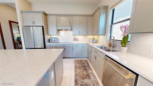 kitchen featuring light stone countertops, appliances with stainless steel finishes, custom exhaust hood, and sink