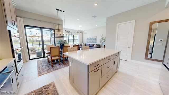 kitchen featuring light tile patterned floors, stainless steel double oven, a kitchen island, a chandelier, and pendant lighting