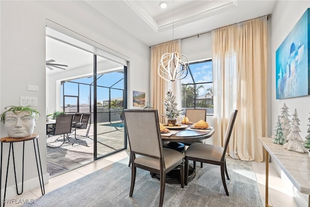 tiled dining room with ceiling fan with notable chandelier, a tray ceiling, and crown molding