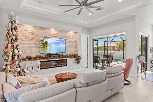 living room featuring ceiling fan, a raised ceiling, light tile patterned floors, and crown molding