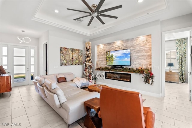 tiled living room with ceiling fan, a healthy amount of sunlight, and a raised ceiling