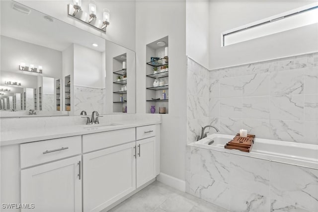 bathroom with built in shelves, vanity, and tiled tub