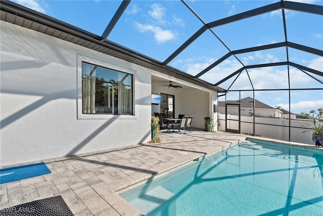 view of swimming pool featuring glass enclosure, ceiling fan, and a patio area