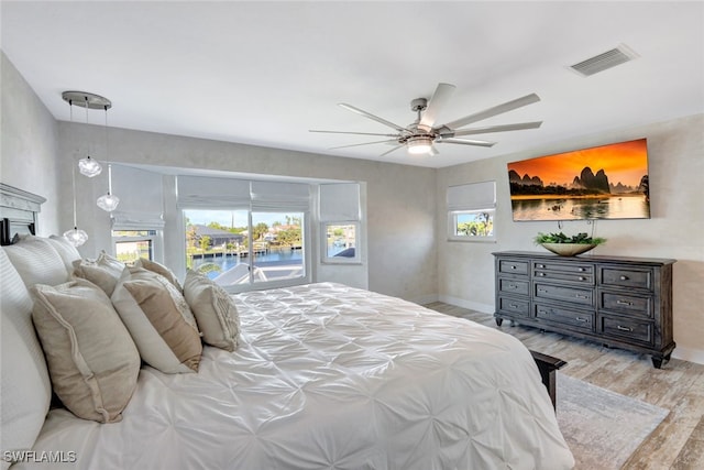 bedroom featuring access to outside, ceiling fan, a water view, and light hardwood / wood-style floors