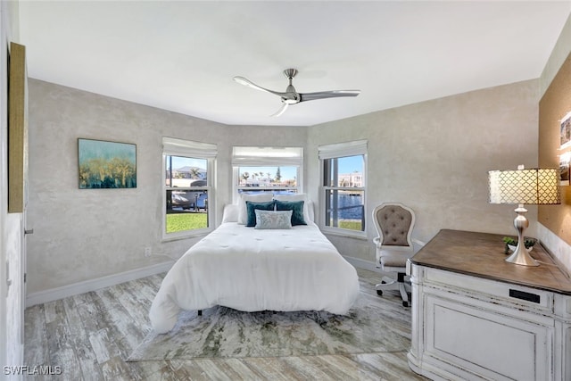 bedroom with light hardwood / wood-style floors, multiple windows, and ceiling fan