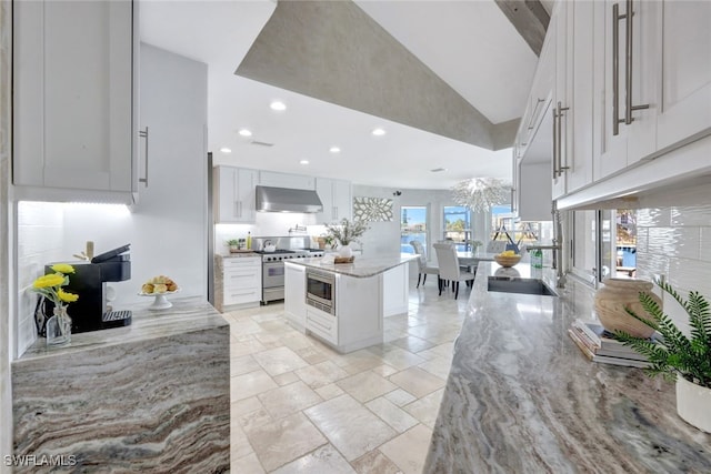 kitchen featuring white cabinetry, stainless steel appliances, light stone counters, ventilation hood, and a kitchen island