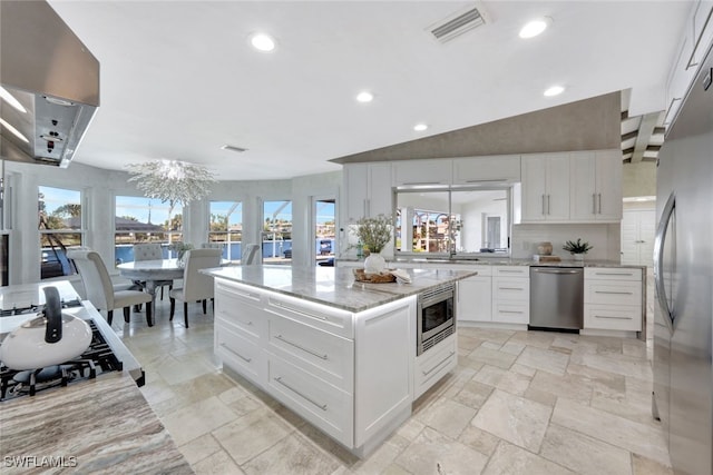 kitchen with a chandelier, built in appliances, white cabinetry, and plenty of natural light