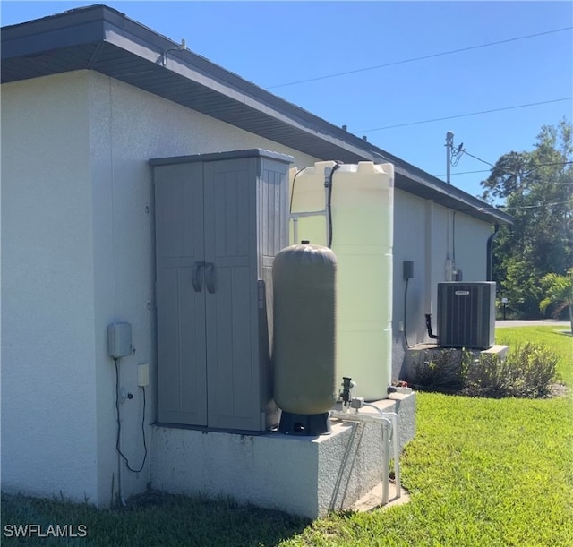 view of side of home featuring a yard, central AC unit, and a storage unit