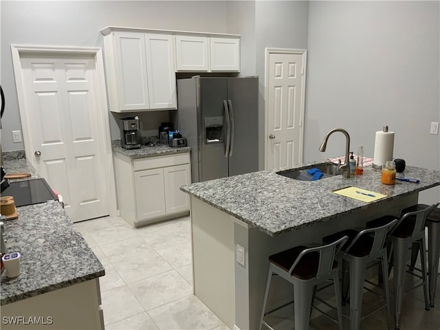 kitchen featuring stainless steel fridge with ice dispenser, sink, white cabinets, and light stone countertops