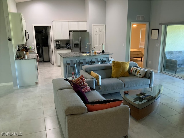 tiled living room with a towering ceiling and sink