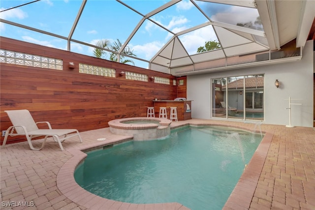 view of pool with a lanai, a patio area, and an in ground hot tub