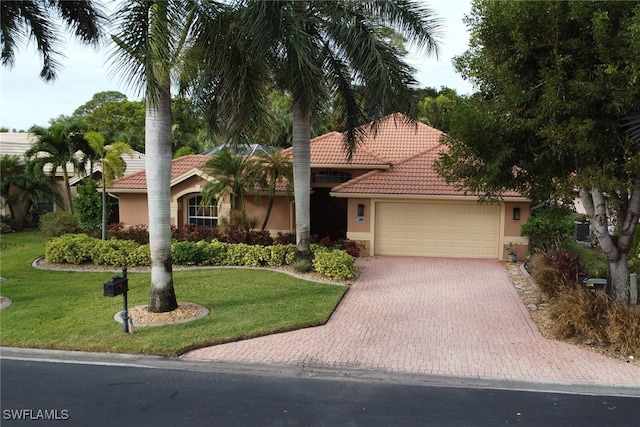 mediterranean / spanish-style house with central AC unit, a garage, and a front lawn