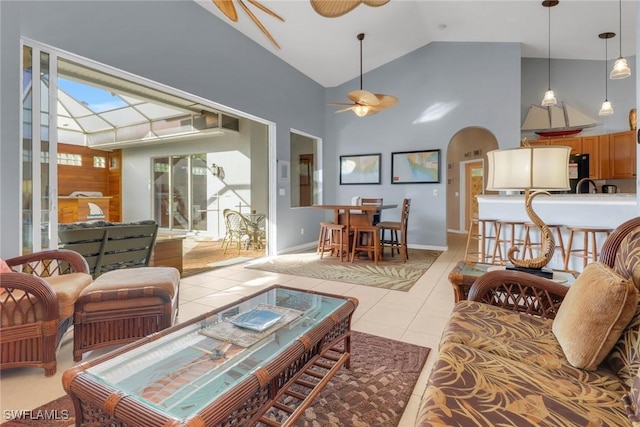 tiled living room with ceiling fan and high vaulted ceiling