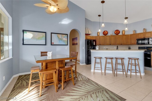 tiled dining space with ceiling fan and a towering ceiling