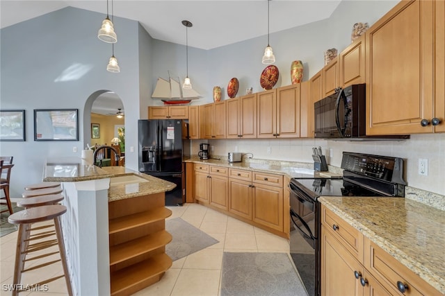 kitchen featuring pendant lighting, a kitchen breakfast bar, a kitchen island with sink, and black appliances