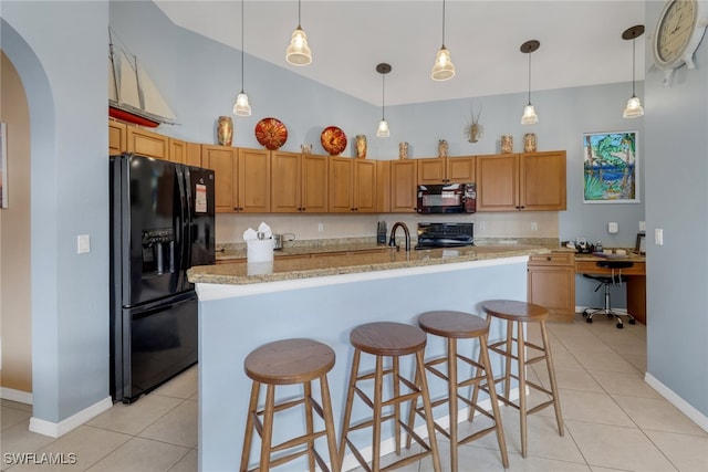 kitchen featuring an island with sink, decorative light fixtures, light tile patterned floors, and black appliances