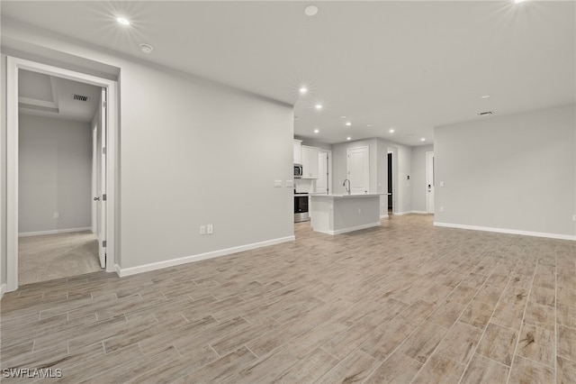 unfurnished living room featuring sink and light wood-type flooring