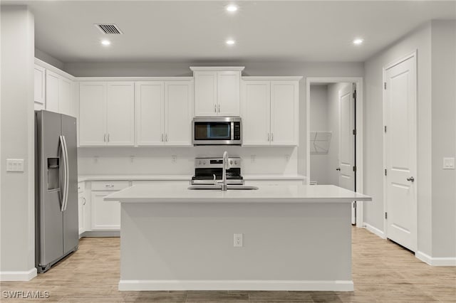 kitchen with white cabinetry, stainless steel appliances, and a kitchen island with sink