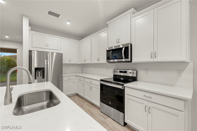 kitchen featuring white cabinetry, sink, light hardwood / wood-style floors, and appliances with stainless steel finishes