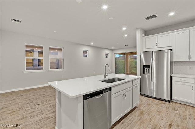 kitchen featuring light wood-type flooring, stainless steel appliances, sink, a center island with sink, and white cabinetry