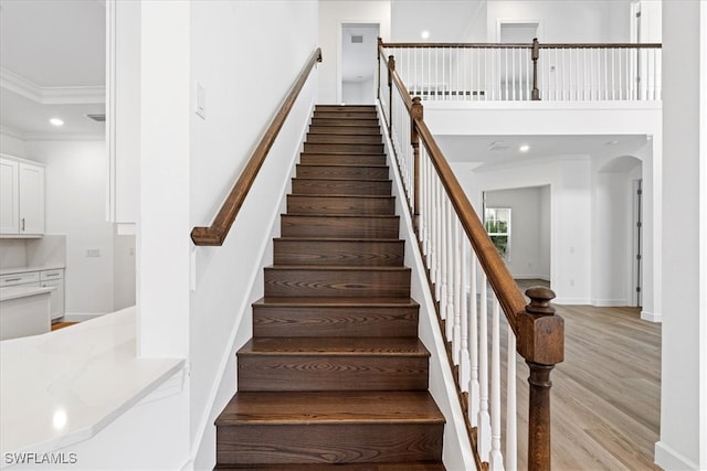 stairway with hardwood / wood-style floors and crown molding