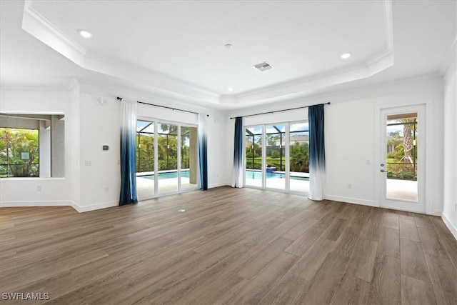 spare room with a tray ceiling, wood-type flooring, and ornamental molding