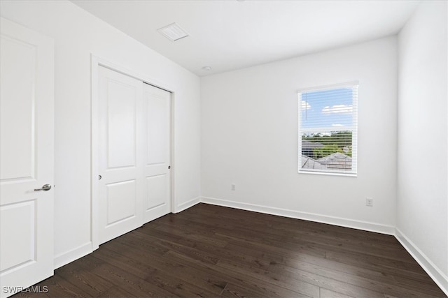 unfurnished bedroom with a closet and dark wood-type flooring