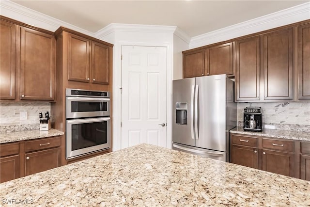 kitchen with backsplash, stainless steel appliances, light stone counters, and crown molding