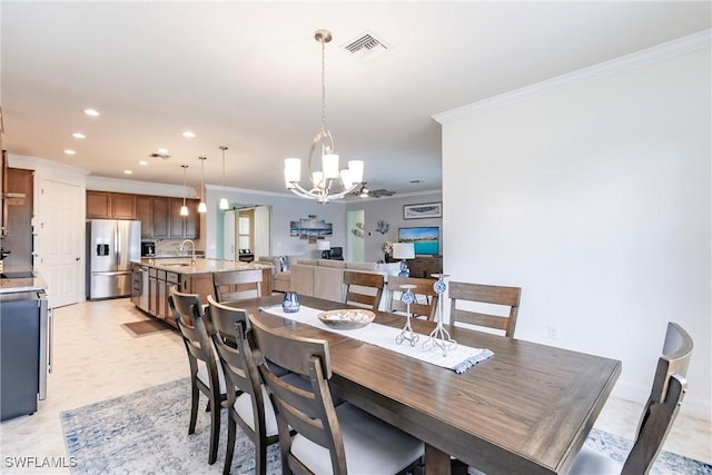 dining space featuring ceiling fan with notable chandelier, crown molding, and sink