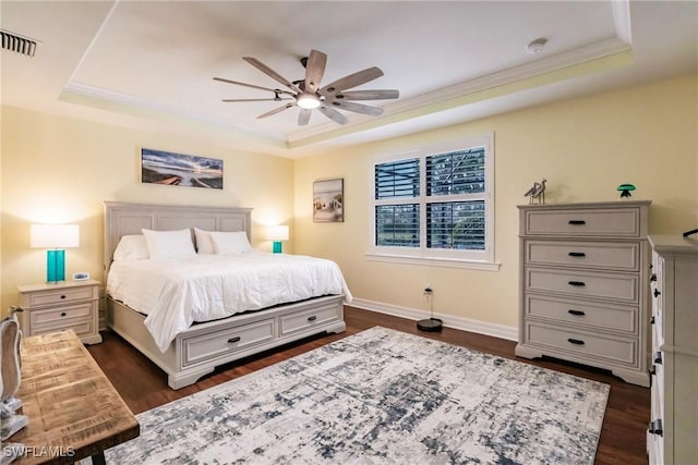 bedroom with ceiling fan, dark hardwood / wood-style flooring, ornamental molding, and a tray ceiling