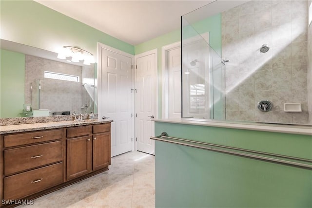 bathroom with a tile shower, vanity, tile patterned floors, and a healthy amount of sunlight