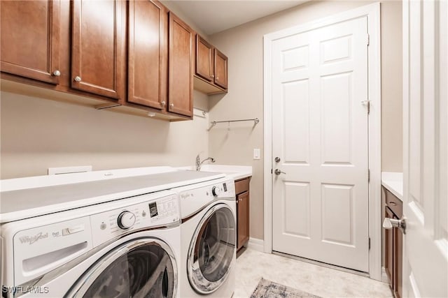 laundry area with cabinets, light tile patterned floors, washing machine and dryer, and sink