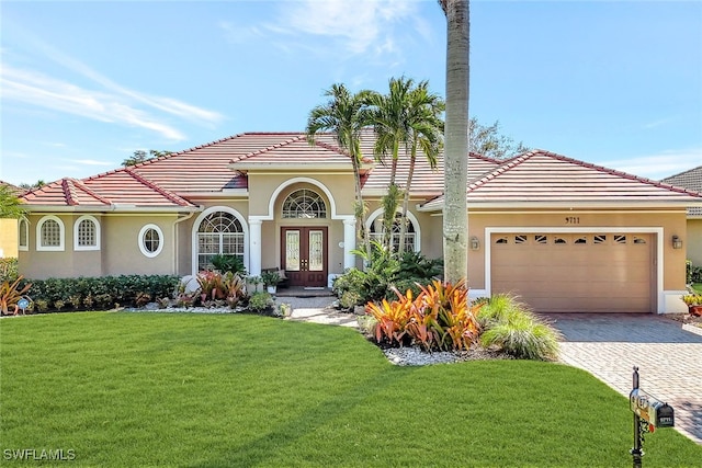 mediterranean / spanish-style home with french doors, a garage, and a front lawn