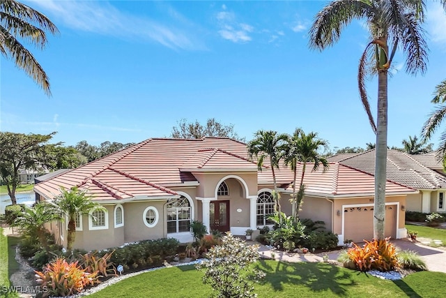 mediterranean / spanish home featuring a front yard and a garage