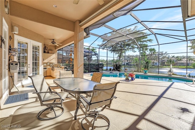 view of patio / terrace featuring a water view, glass enclosure, and ceiling fan