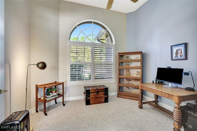 office space featuring carpet flooring, ceiling fan, and a towering ceiling