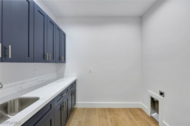 laundry area with hookup for an electric dryer, sink, cabinets, and light wood-type flooring