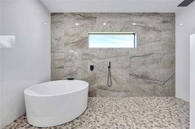 bathroom with tile walls and shower with separate bathtub