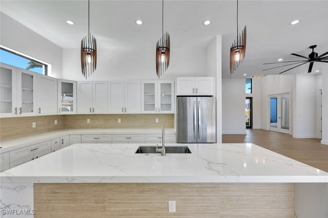 kitchen with pendant lighting, sink, ceiling fan, stainless steel fridge, and white cabinetry