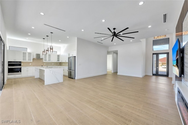 kitchen featuring white cabinets, stainless steel appliances, decorative light fixtures, and light wood-type flooring