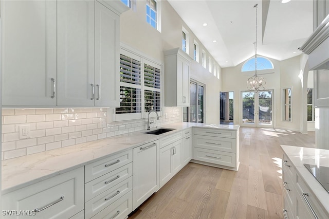 kitchen featuring a healthy amount of sunlight, white cabinetry, sink, and high vaulted ceiling