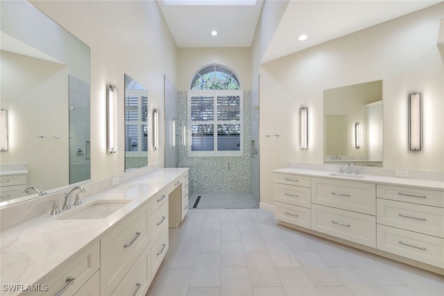 bathroom featuring tile patterned flooring, vanity, and a tile shower