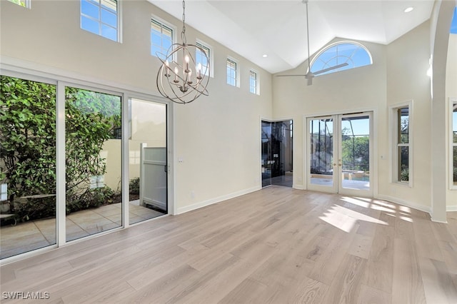 interior space featuring french doors, light wood-type flooring, high vaulted ceiling, and a notable chandelier