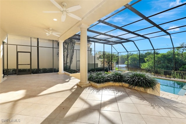 view of patio with ceiling fan, a lanai, and a water view